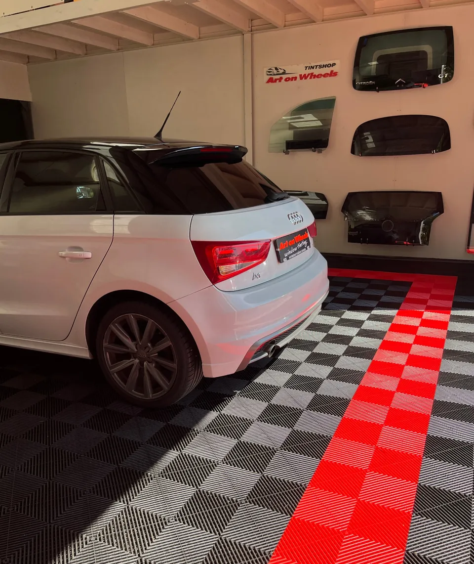 Witte Audi A1 met getinte ruiten voor de wand met voorbeeldruiten