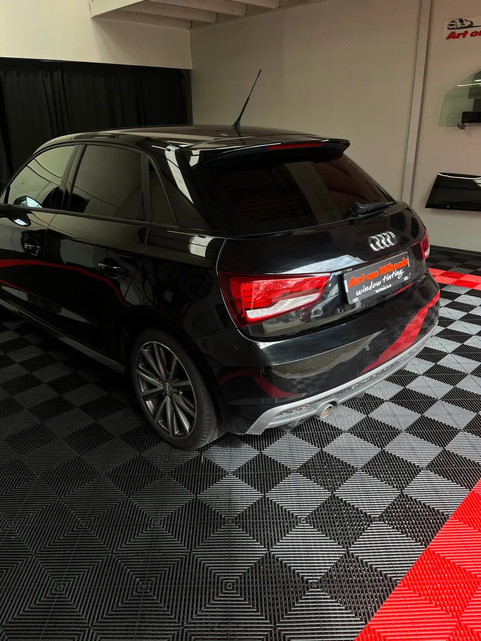 Zwarte Audi A1 met getinte ruiten op de tegelvloer van de showroom